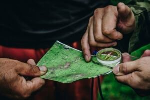 Hands holding a map and compass outdoors